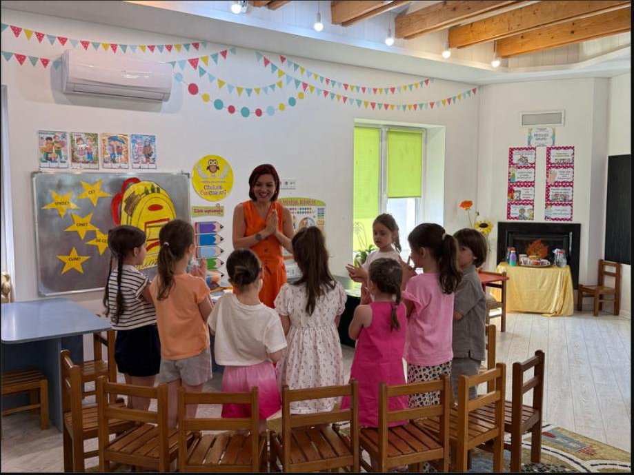 Educatoare și copii într-o sală de clasă decorată festiv