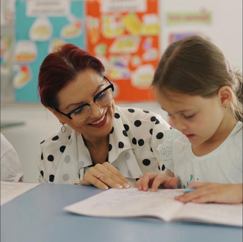 Educatoare ajutând un copil la Grupa Mare